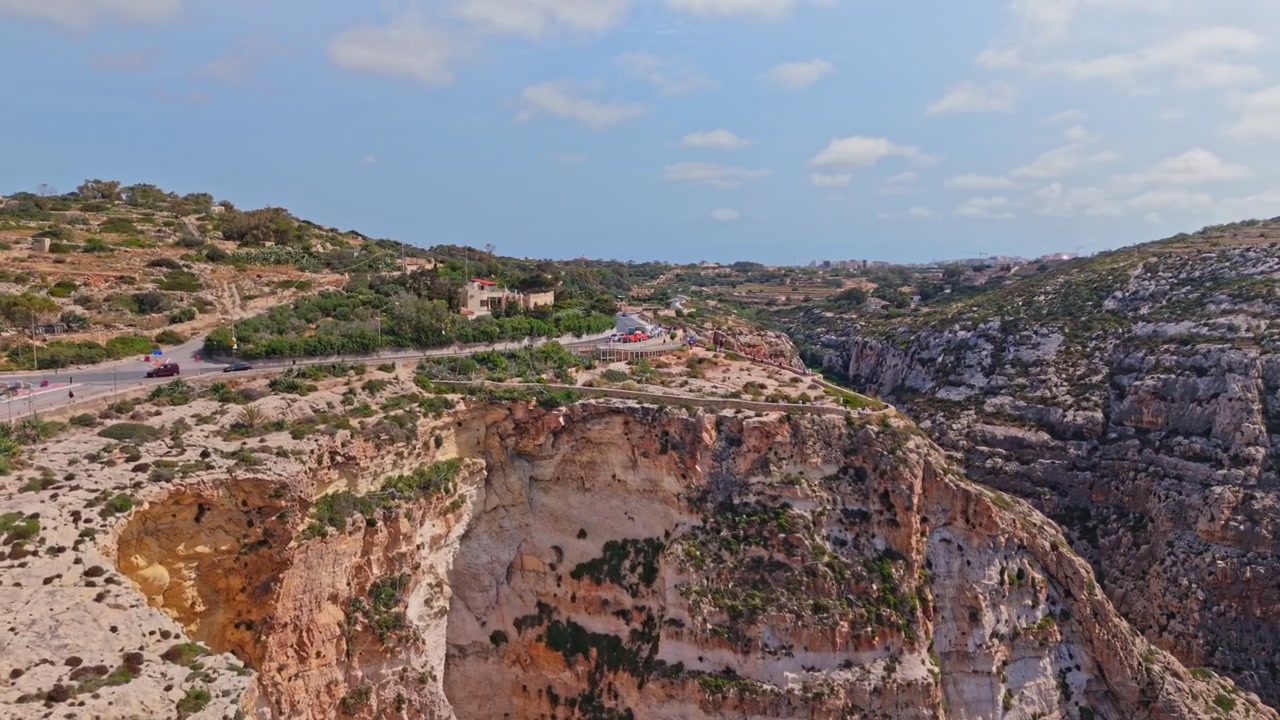 La Gruta Azul de Malta, un majestuoso arco natural de piedra caliza y complejo de cuevas marinas en la costa sur. Vistas aéreas panorámicas muestran aguas de un azul profundo contrastando con acantilados escarpados y bañados por el sol.