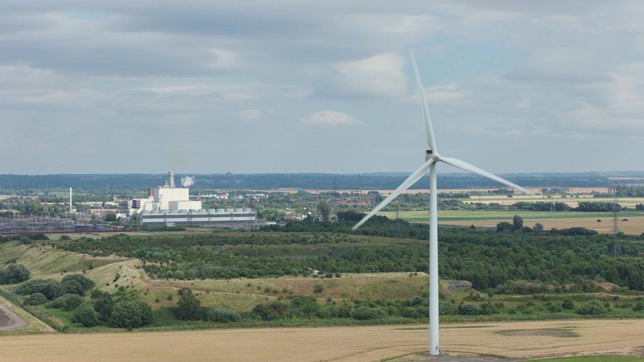 Wind Turbine Spinning in Rural Landscape Near Industrial Complex