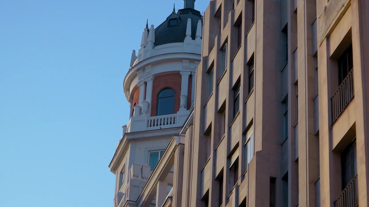 Toma de ángulo bajo de arquitectura histórica española con una cúpula decorativa junto a edificios de apartamentos modernos en Madrid. Perfecto para documentales de viajes y contenido de estilo de vida urbano