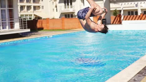 young athletic man in swim shorts running and jumping spinning to the swimming pool. slowmotion shot.