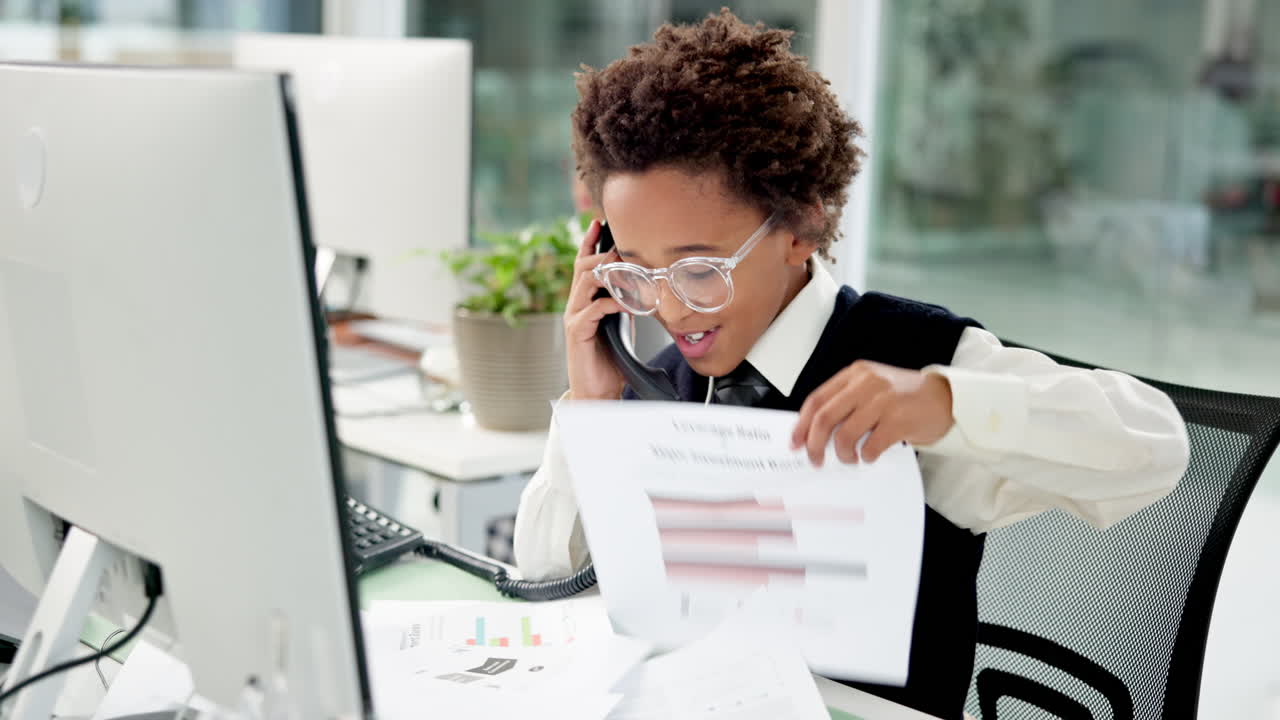 Young boy in office attire taking a phone call at a desk
