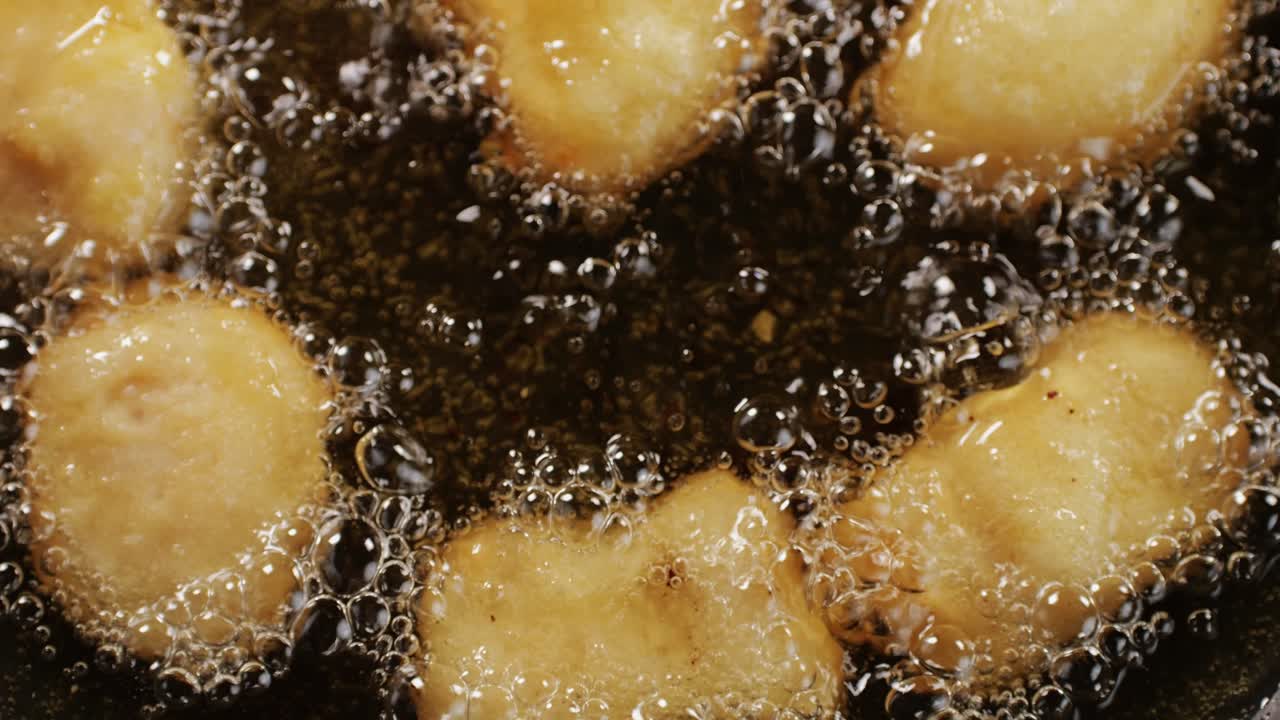 American chiken nuggets broiling on black frying pan top view. Breaded nagget of chiken meat. Man cooking fast food. High quality 4k footage