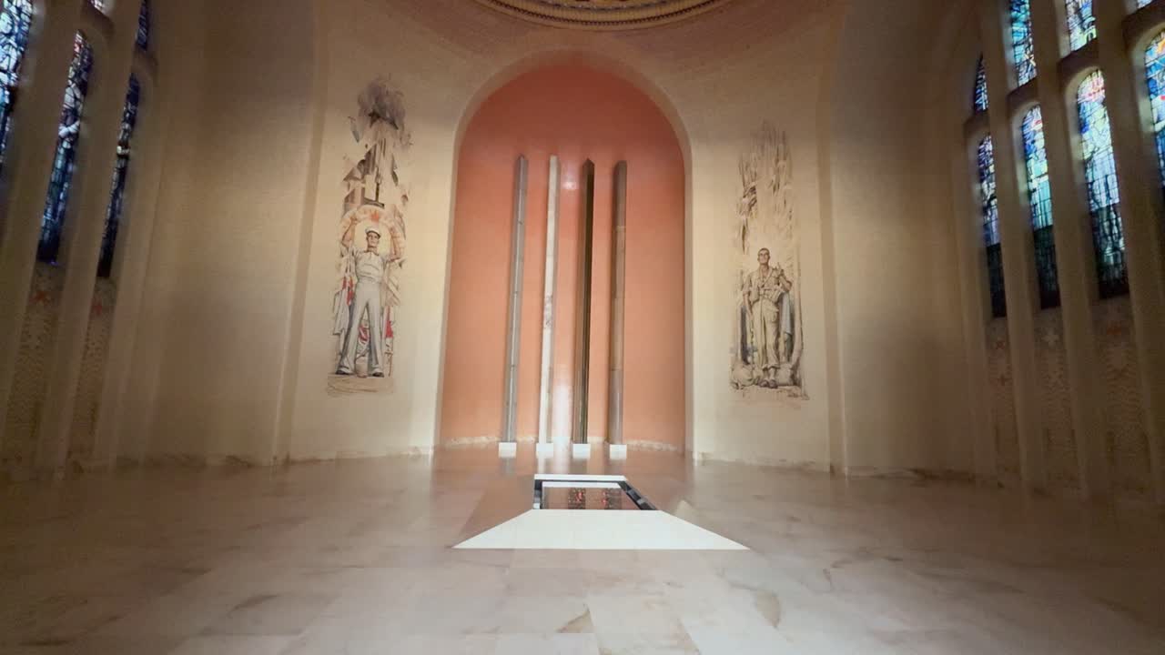 Una ripresa grandangolare si sposta verso l'alto all'interno di una grande sala a cupola con vetrate colorate