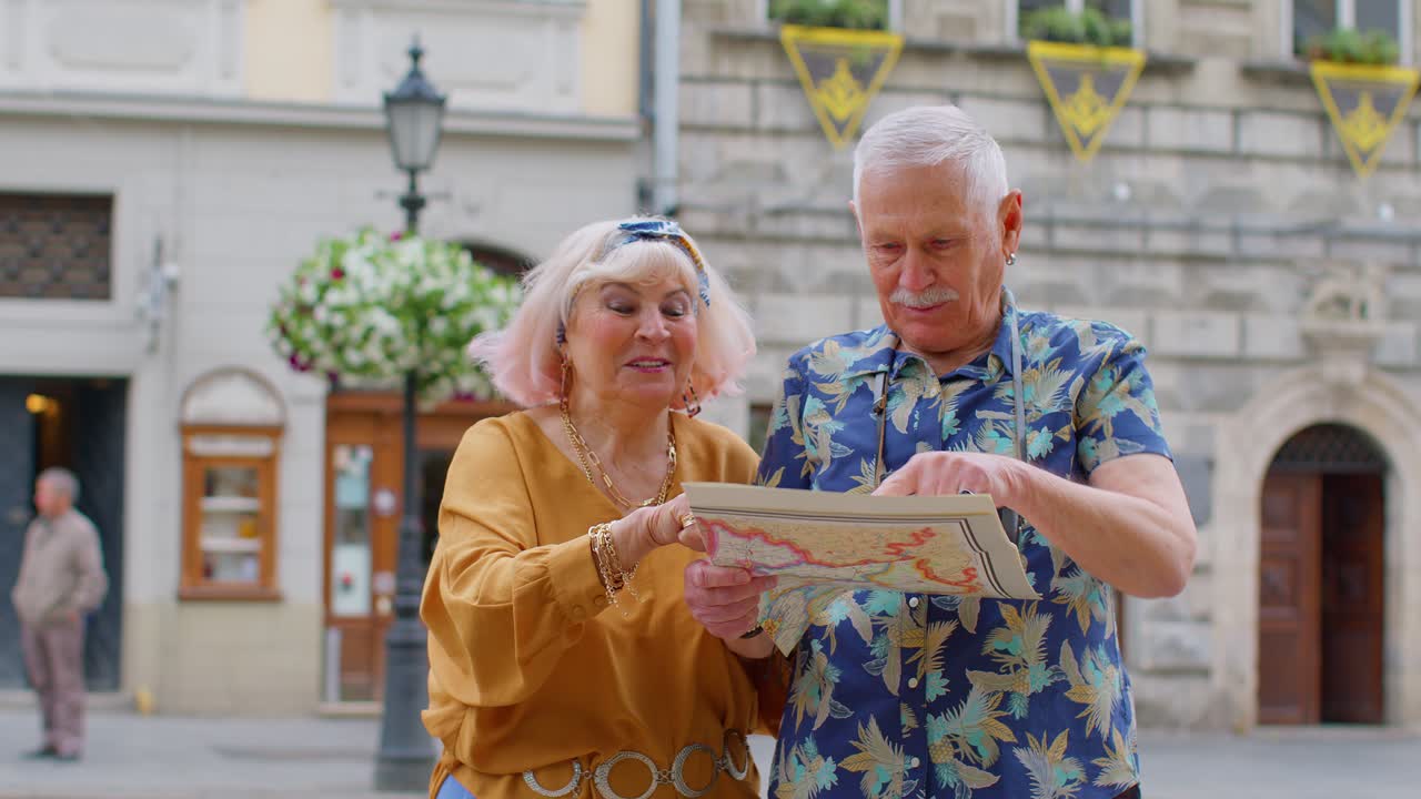 Senior grandmother and grandfather tourists looking for a place to go in new city using paper map