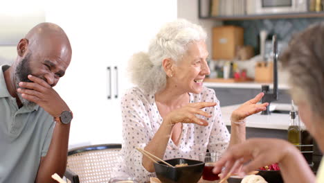 laughing and enjoying meal, senior friends having fun together at home