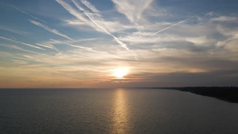 aerial dolly to sunset over calm serene lake as wispy clouds float in sky