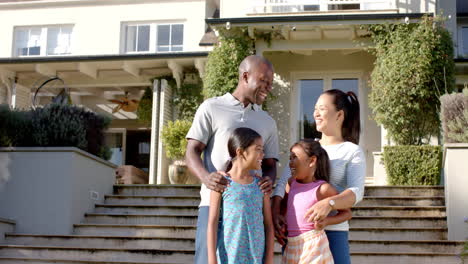 smiling family of four standing together outside their home, enjoying time