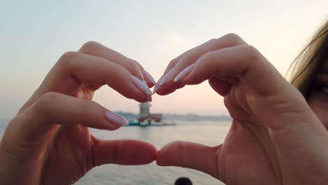 slow motion:beautiful girl makes heart shape with view of maiden tower inside in istanbul, turkey