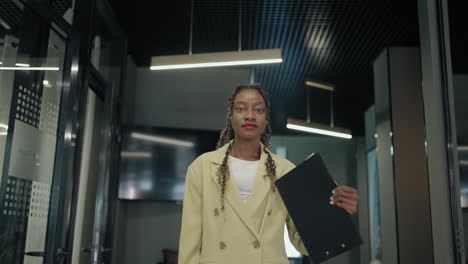 beautiful-stylish-black-woman-with-paper-in-office-corridor-portrait-of-female-office-worker