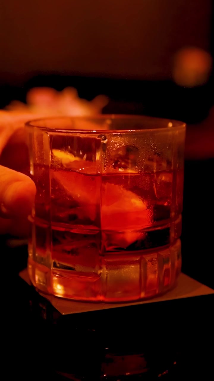 Mano che regge un bicchiere da cocktail in un bar in penombra
