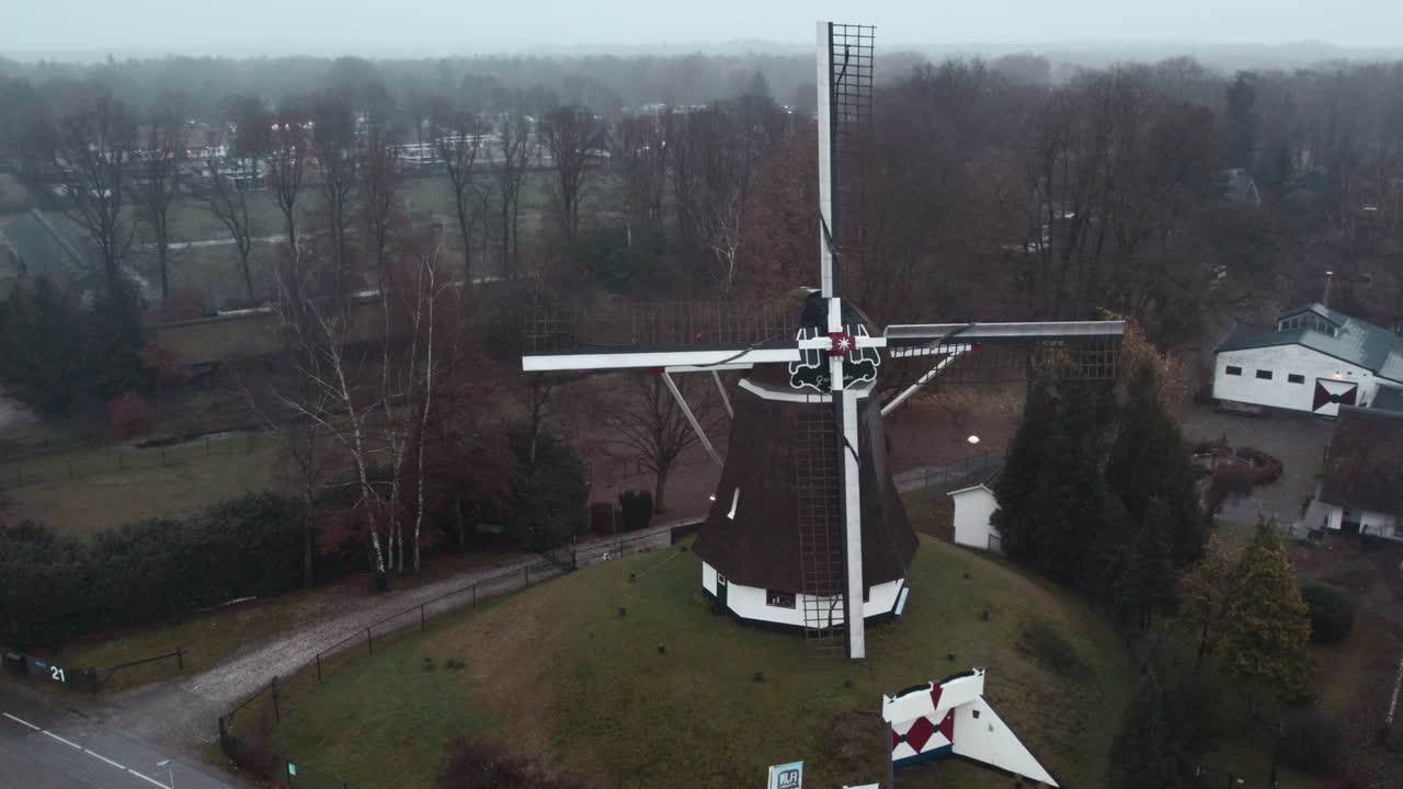 Arc shot from a drone of a traditional Dutch windmill standing in traditional Dutch rain.
