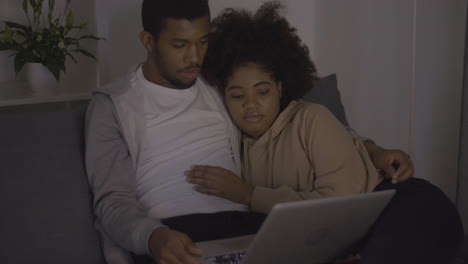 pareja joven viendo una película en la computadora portátil