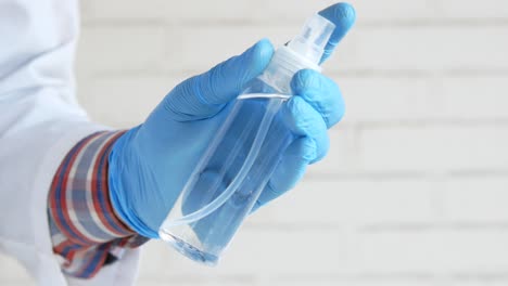 person holding a spray bottle of hand sanitizer in blue gloves