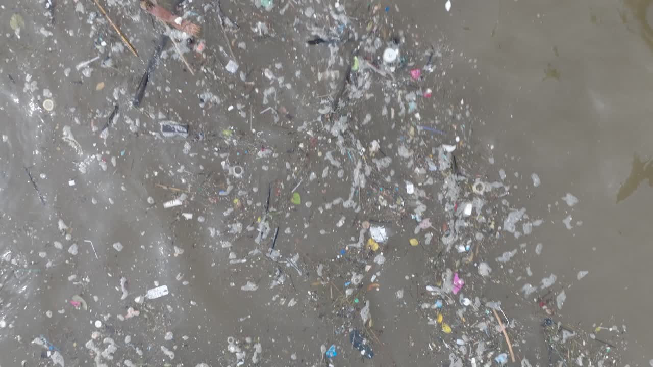 fotografía de avión no tripulado de baja altitud de arriba hacia abajo de un océano contaminado lleno de basura flotante y escombros y escorrentía de aguas residuales fangosas en bali, indonesia
