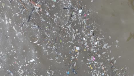 Low-altitude-top-down-drone-shot-of-polluted-ocean-filled-with-floating-trash-and-debris-and-muddy-sewage-runoff-in-Bali-Indonesia