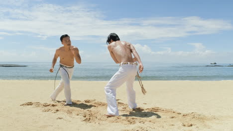 dos hombres bailando capoeira en la playa