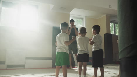 children study block with instructor in martial arts class. little boys protect heads from punches with sensei in gym slow motion. combat school