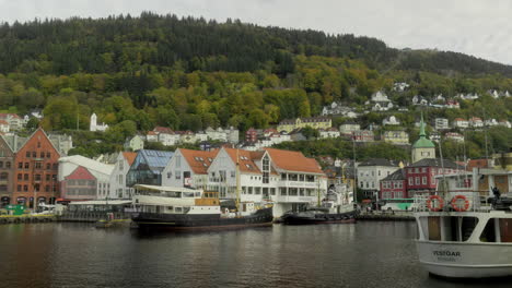 old boats in the harbor of bergen, norway with the famous mount floyen in the background