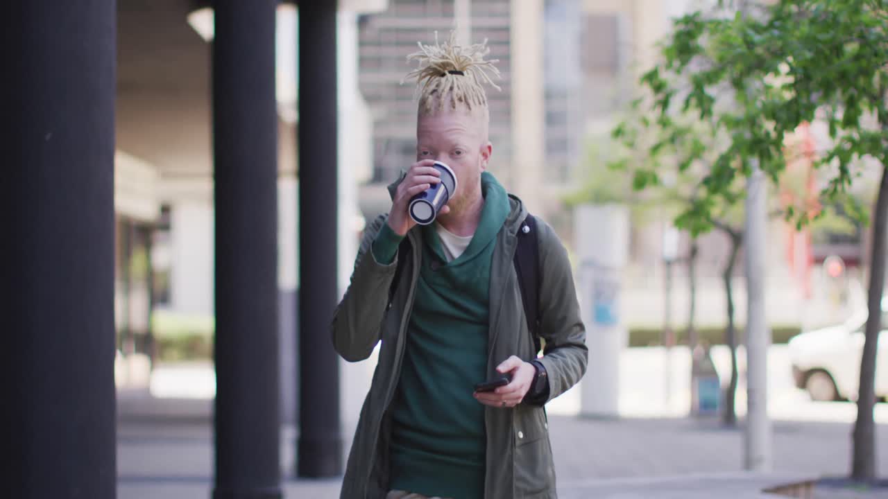 hombre albino afroamericano pensativo con rastas bebiendo café y usando un teléfono inteligente