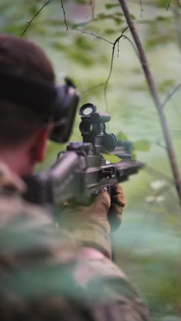 soldier in camouflage uniform aiming with a rifle in the forest