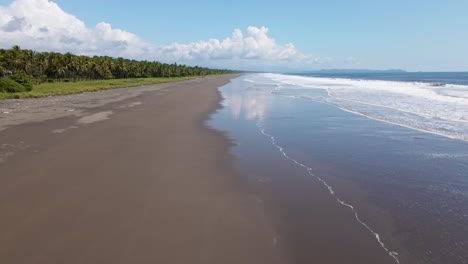 olas del océano rompiendo en la costa mientras el dron acelera hacia adelante