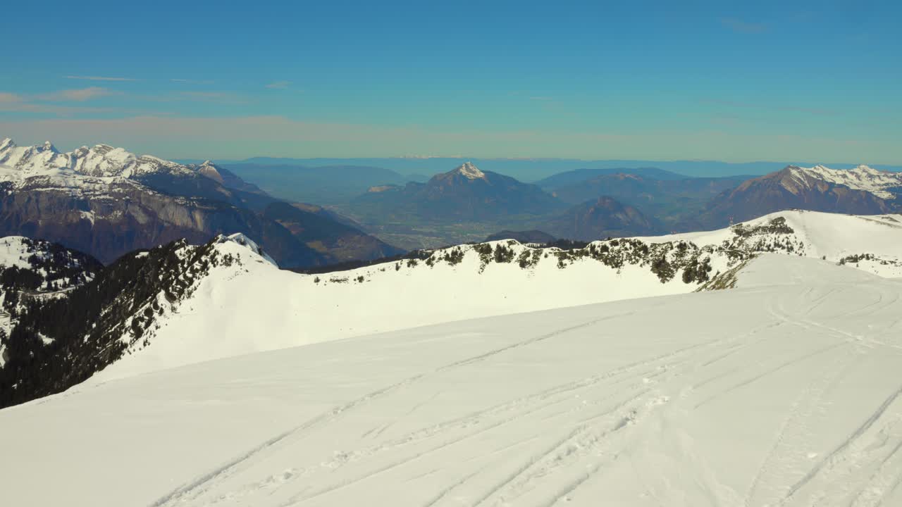 Snowy slope with ski tracks overlooking French alps mountain landscape