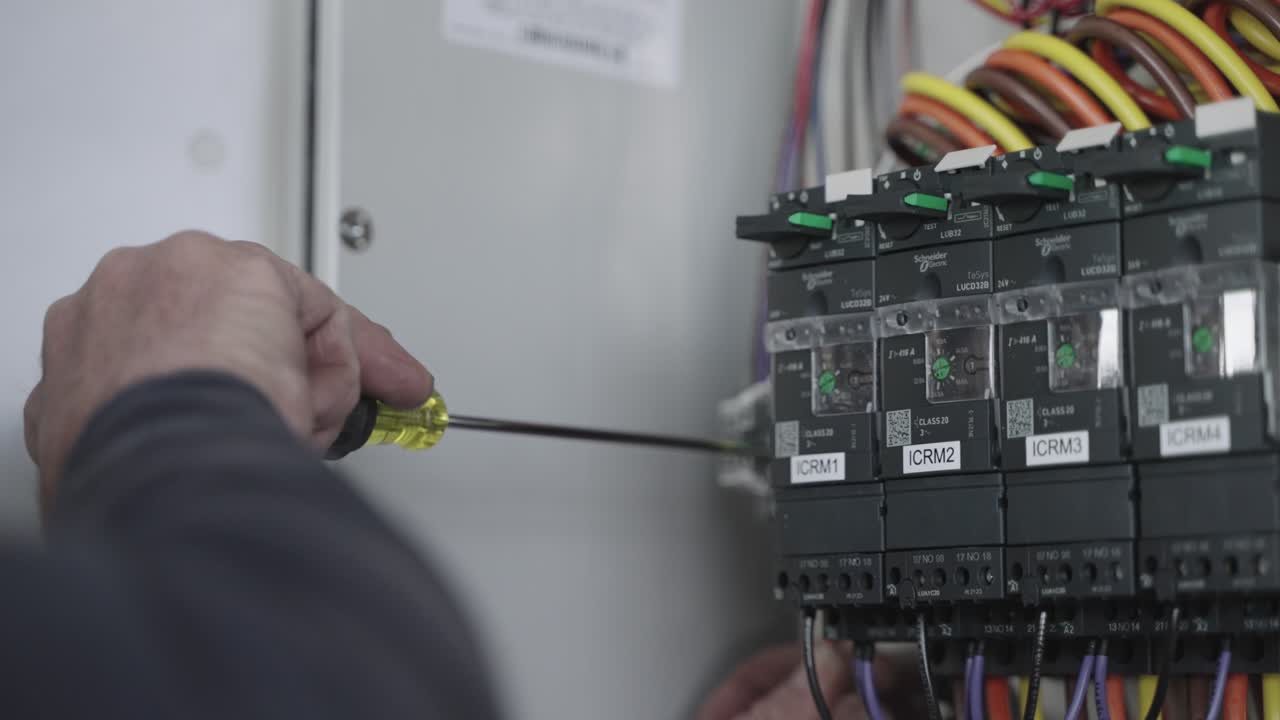 электромеханик использует отвертку для починки распределительной электрической коробки, замедленная съемка