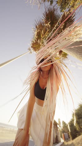 woman with colorful braids under a palm tree on a sunny beach