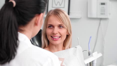 Gespräch-Zwischen-Lächelnder-Frau-Und-Zahnarzt-In-Der-Zahnarztpraxis