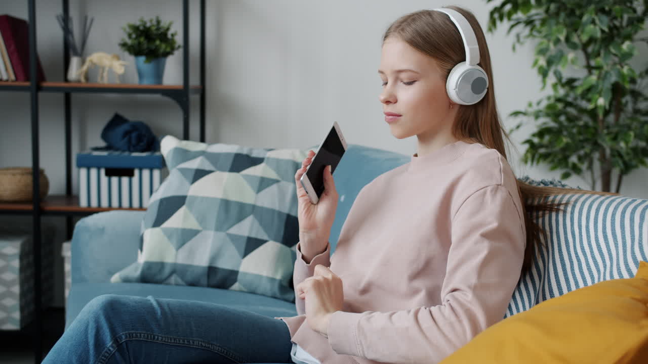Teenage Girl Relaxing on a Couch with Headphones and Smartphone
