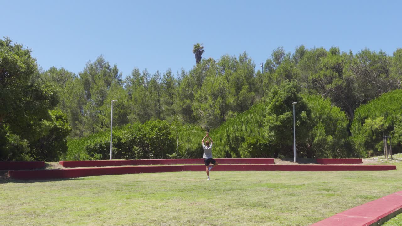 una persona haciendo vrikshasana en un campo de hierba