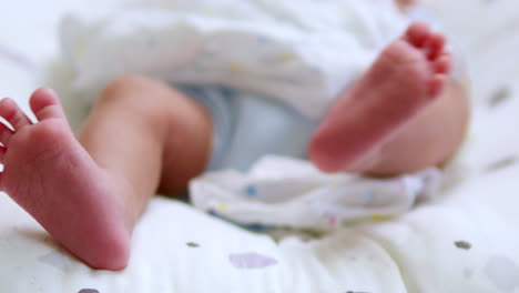 Close-up-shot-of-a-newborn-baby-stretching-her-left-leg-and-then-followed-simultaneously-by-her-right-leg-while-she-is-lying-on-the-bed