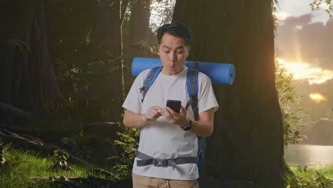 surprised hiker with a backpack looking at smartphone in a forest