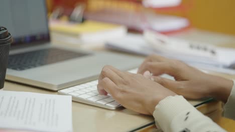 las manos de la mujer de negocios escribiendo en el teclado de la computadora portátil para buscar información, informe de investigación de marketing en el escritorio de la oficina