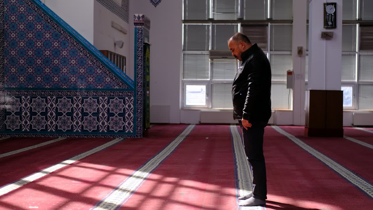 나이든 이슬람 남자가 햇빛 아래 모스크에서 기도한다