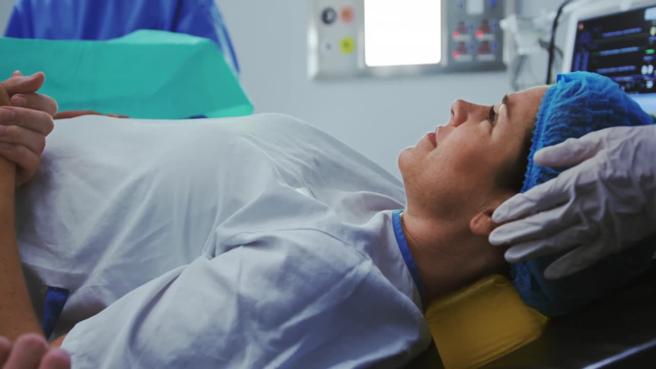 hombre reconfortando a una mujer embarazada durante el parto en el teatro de operaciones en el hospital 4k