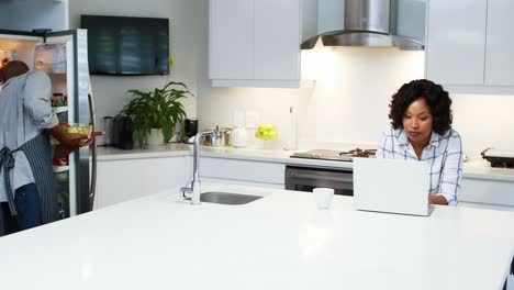 couple using laptop in kitchen 4k