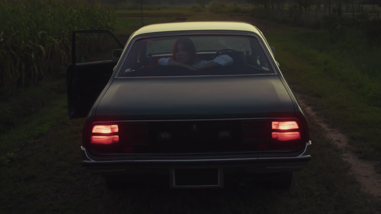 Mujer en coche clásico al atardecer