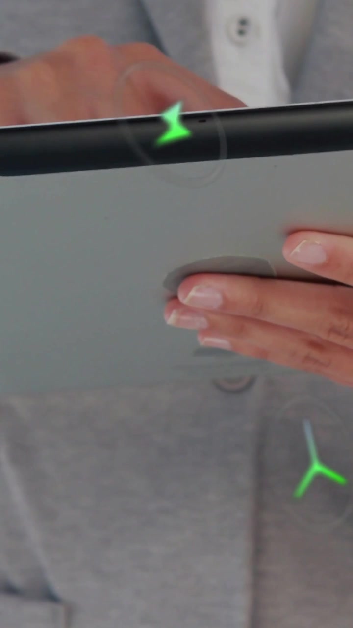 Video verticale: Professionista che tocca la cornice di un tablet in un ambiente tecnologico, facendo apparire icone HUD verdi che seguono il dito.