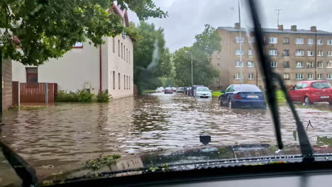 subjective perspective from inside a car driving cautiously through a street flooded by heavy rain