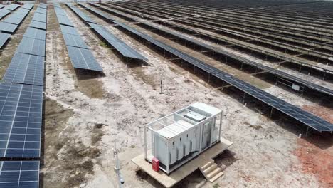 vuelo aéreo de drones sobre un parque solar en gambia, áfrica, en cámara lenta, pasando por un inversor de voltaje medio industrial