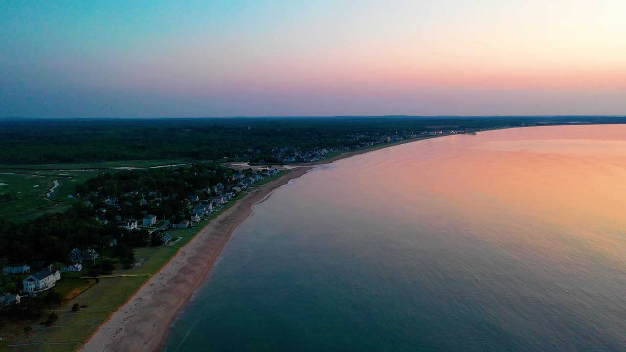 vista aérea del amanecer sobre las casas de playa con colores que se reflejan en las olas del océano y las casas de vacaciones a lo largo de la costa atlántica de nueva inglaterra
