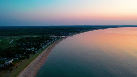 Vista-Aérea-Por-Drones-Del-Amanecer-Sobre-Casas-De-Playa-Con-Colores-Que-Se-Reflejan-En-Las-Olas-Del-Océano-Y-Casas-De-Vacaciones-A-Lo-Largo-De-La-Costa-Atlántica-De-Nueva-Inglaterra