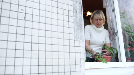 woman in open window planting a house plant