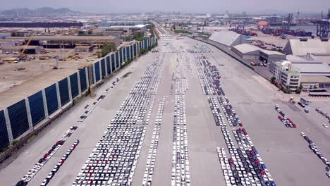 Aerial-view-of-logistics-concept-of-commercial-vehicles,-cars-and-pickup-trucks-waiting-to-be-load-on-to-a-roll-on-roll-off-car-carrier-ship