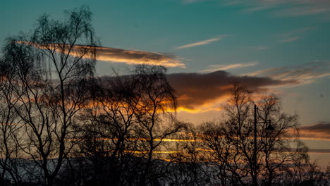 el atardecer transcurre sobre glasgow, escocia, nubes cálidas sobre un cielo fresco con árboles.
