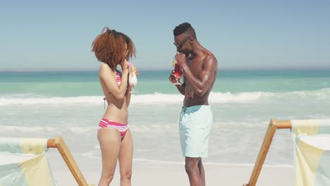African american couple drinking cocktail seaside