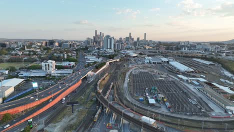 Drone-shot-tracking-train-crossing-Brisbane-City-Mayne-Railway-yard-as-camera-pulls-away-revealing-trains-driving-below