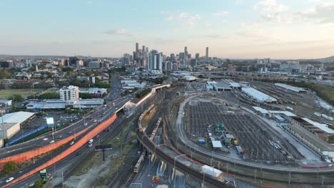 drone shot tracking train crossing brisbane city mayne railway yard as camera pulls away revealing trains driving below