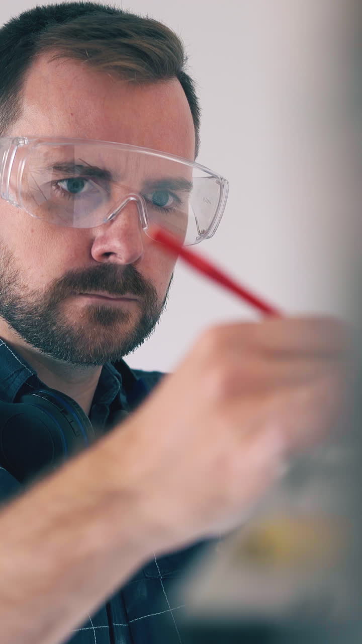 CU, Dolly shot: concentrated builder in transparent goggles tired of checking wall angle with level in empty room closeup